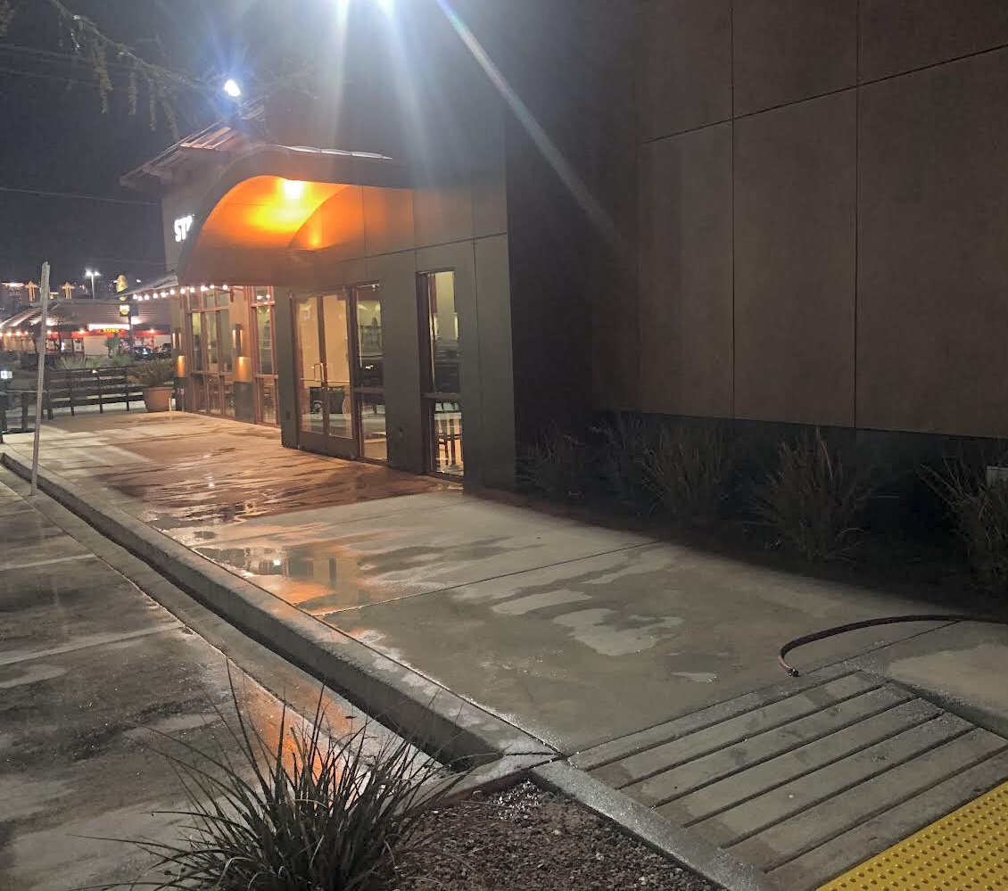 Freshly pressure-washed sidewalk outside a Starbucks at night