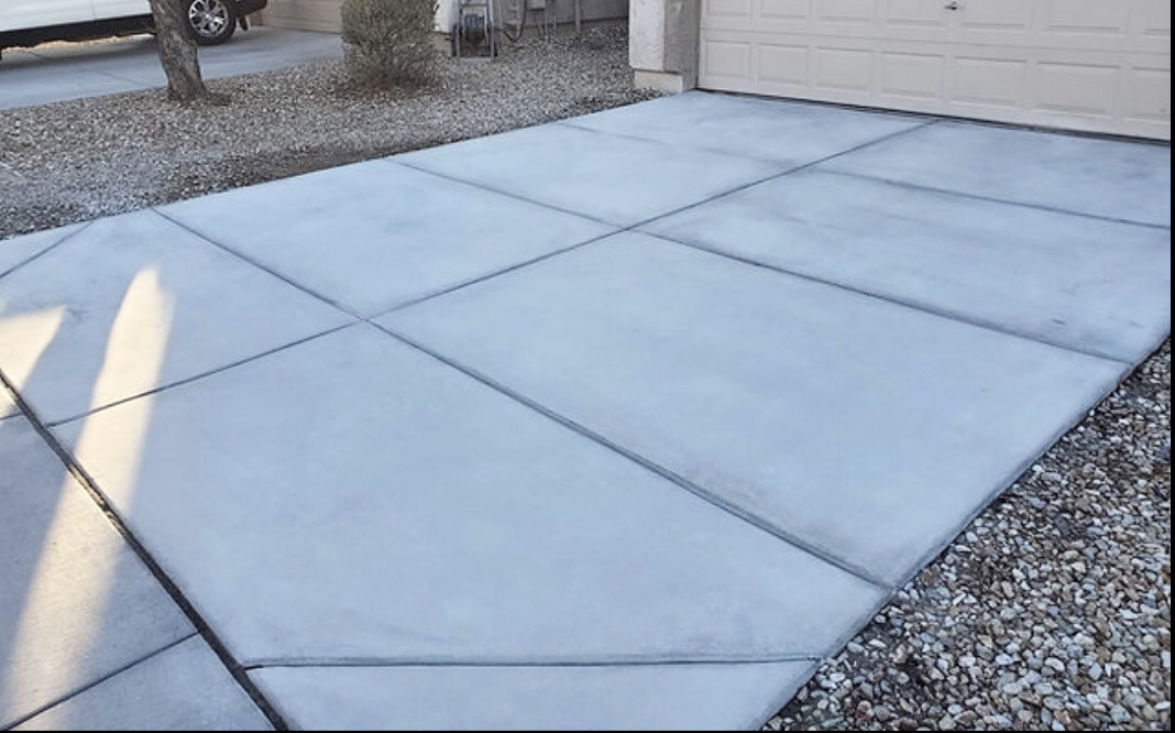 Newly cleaned residential concrete driveway next to gravel